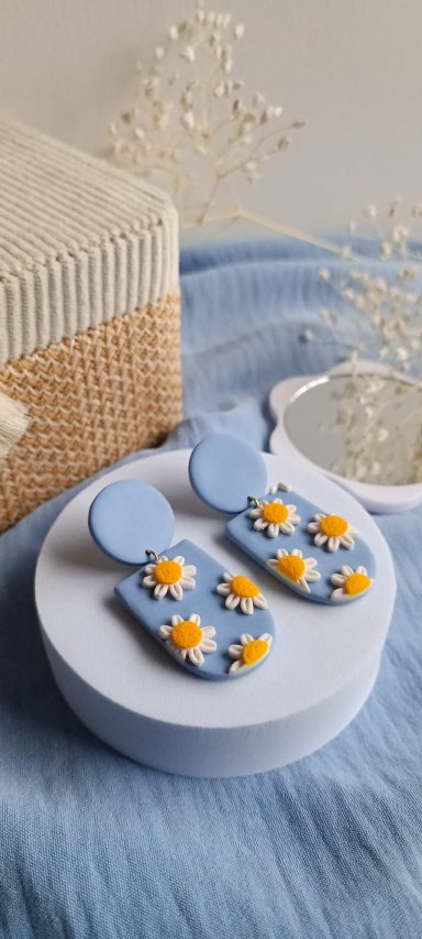 Sandales bleues avec embellissements floraux jaunes sur un fond doux et texturé.