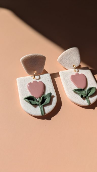 Boucles d'oreilles avec motif de fleur rose sur fond clair.