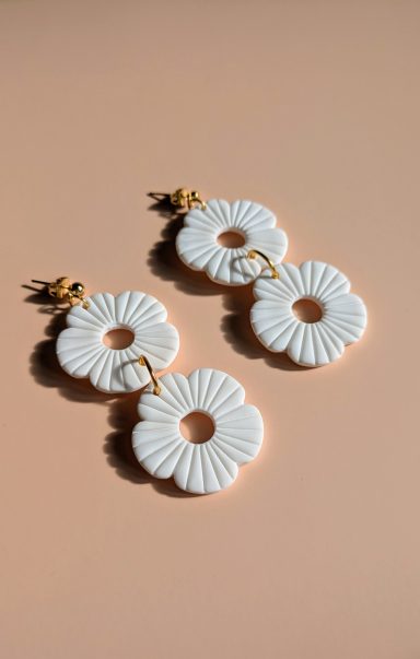 Boucles d'oreilles blanches en forme de fleurs avec des détails texturés.
