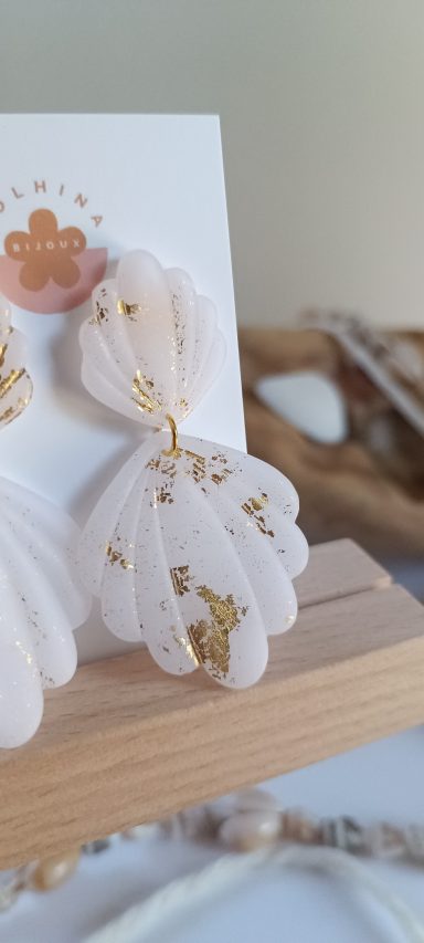 Boucles d'oreilles en forme de feuilles blanches avec des détails dorés.